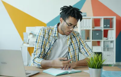 Man working at a desk with laptop and notebook