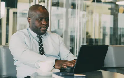 Man typing on laptop with coffee cup nearby