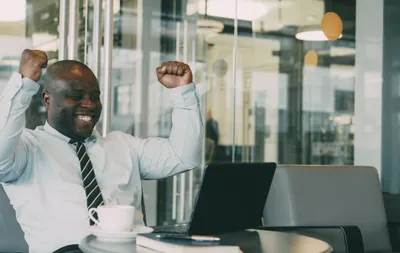 Man celebrating success in office with laptop
