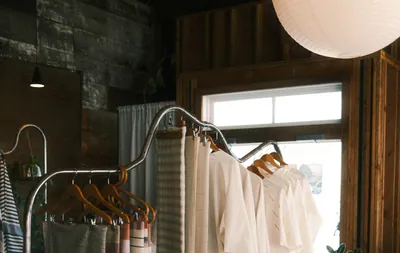 Textiles and clothing on a metal rack in a sunlit boutique shop