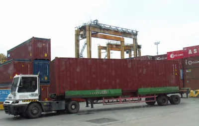 A truck carrying a large shipping container at a port